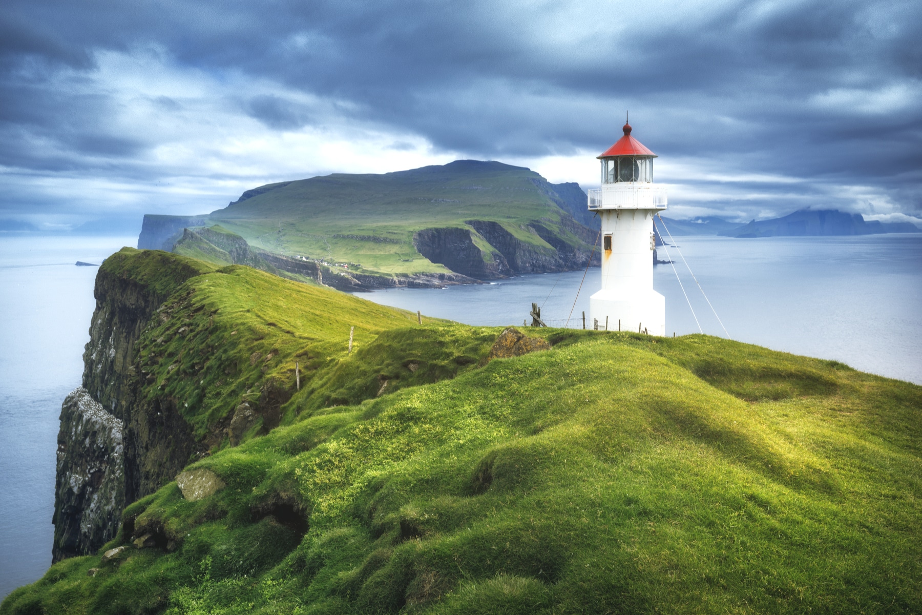 Dramatische Klippenlandschaft der Färöer beim Leuchtturm von Mykines. Das Archipel lässt sich von Tórshavn aus mit dem Auto gut erkunden.